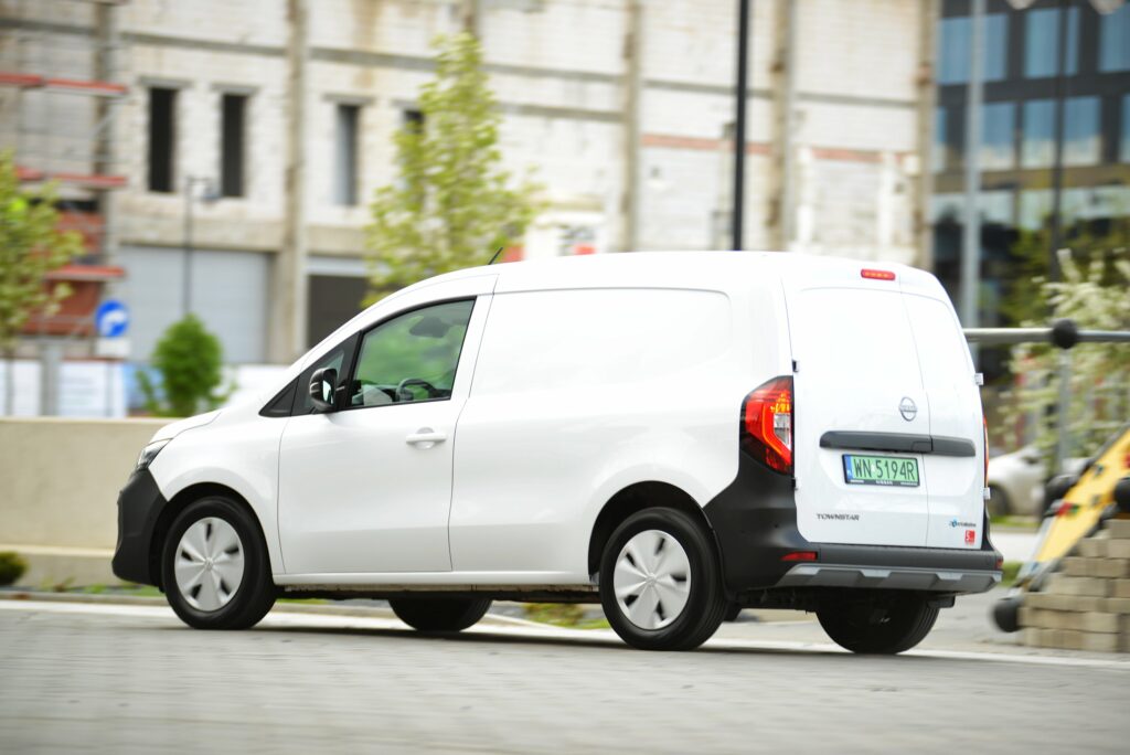 Biały elektryczny Nissan Townstar w wersji dostawczej jedzie po ulicy