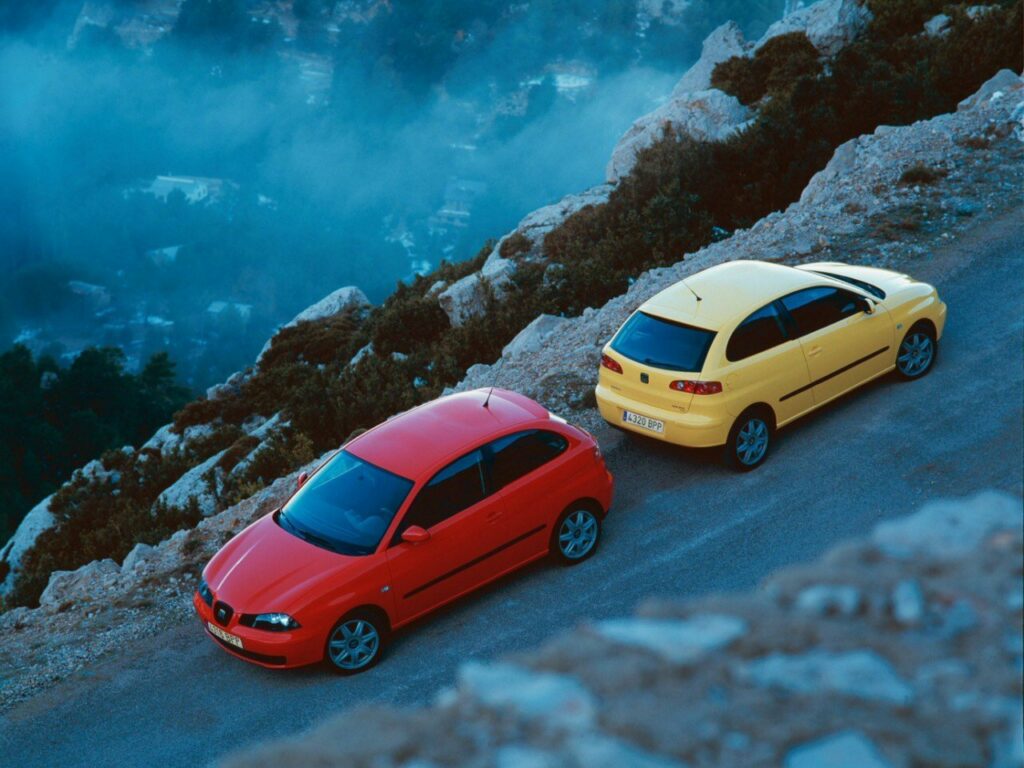 dwa Seaty Ibiza III czerwony i żółty stojące na drodze nad urwiskiem