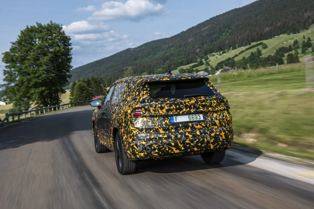 zamaskowana Škoda Kodiaq drugiej generacji jedzie po drodze w górach