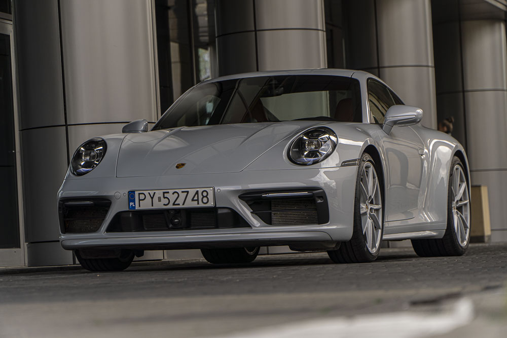 szare Porsche 911 Carrera stoi pod eleganckim budynkiem