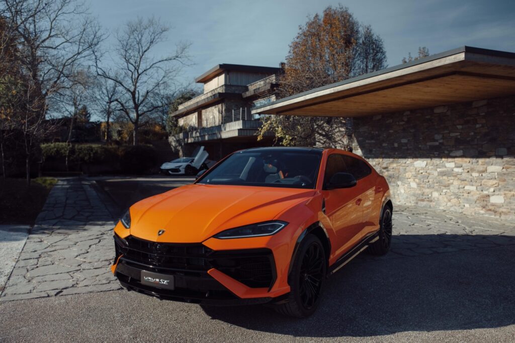 pomarańczowe Lamborghini Urus SE stojące pod domem
